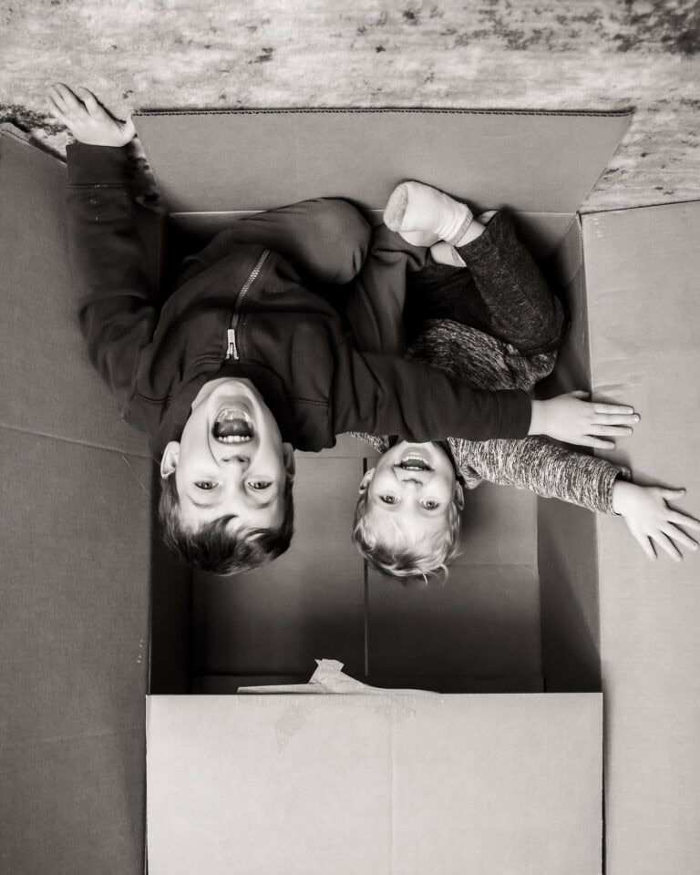 Upside down image of two children shouting as they jump from a box