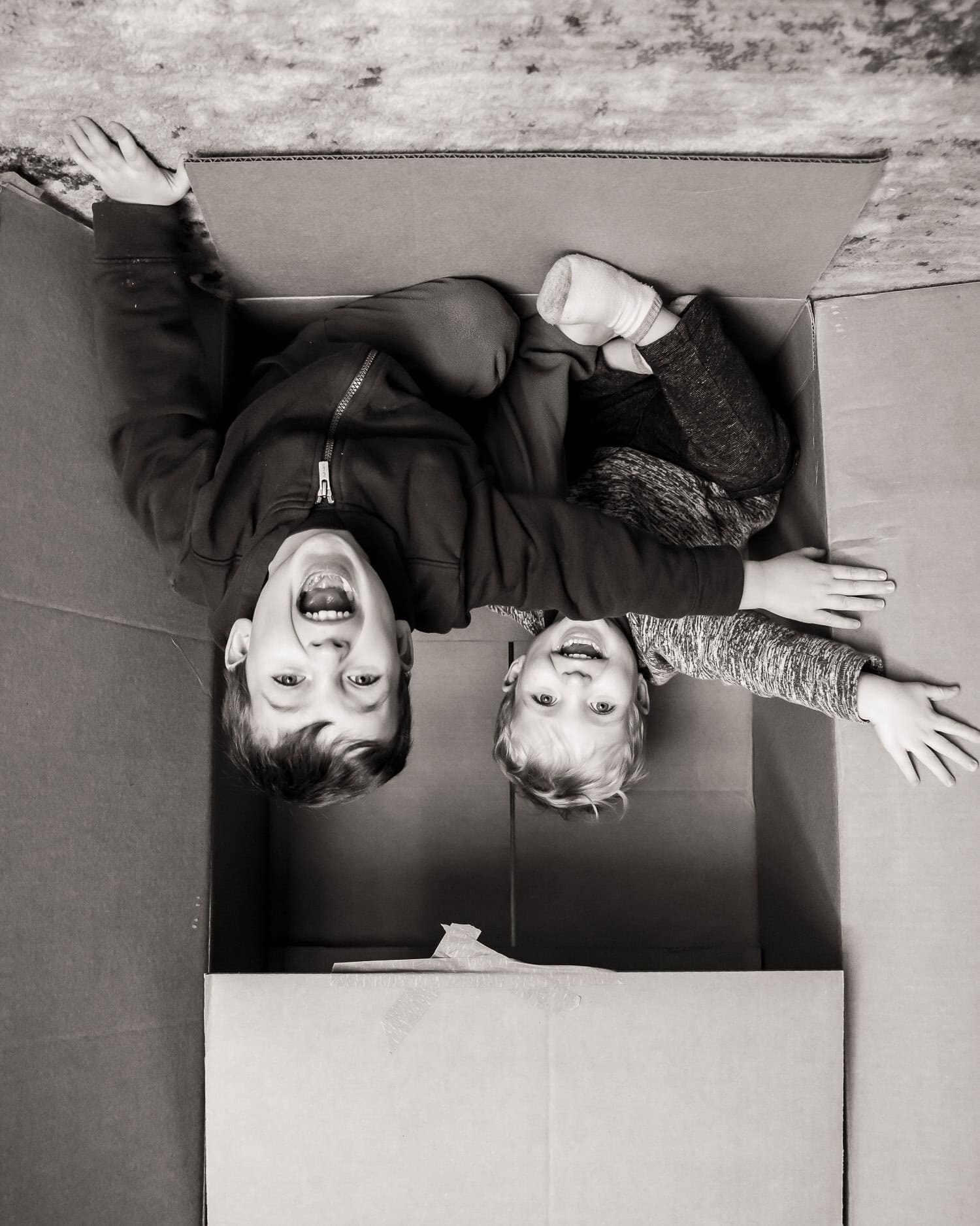 Upside down image of two children shouting as they jump from a box