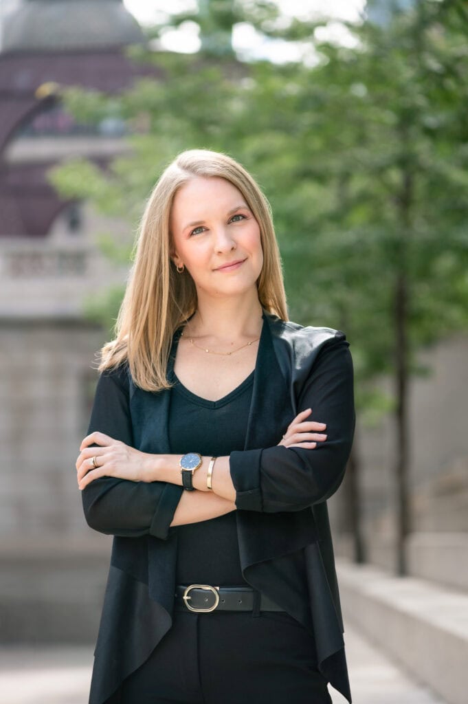 retouched photo of woman wearing black stands with arms crossed by the chicago riverwalk during a branding photo session for her magazine editorial