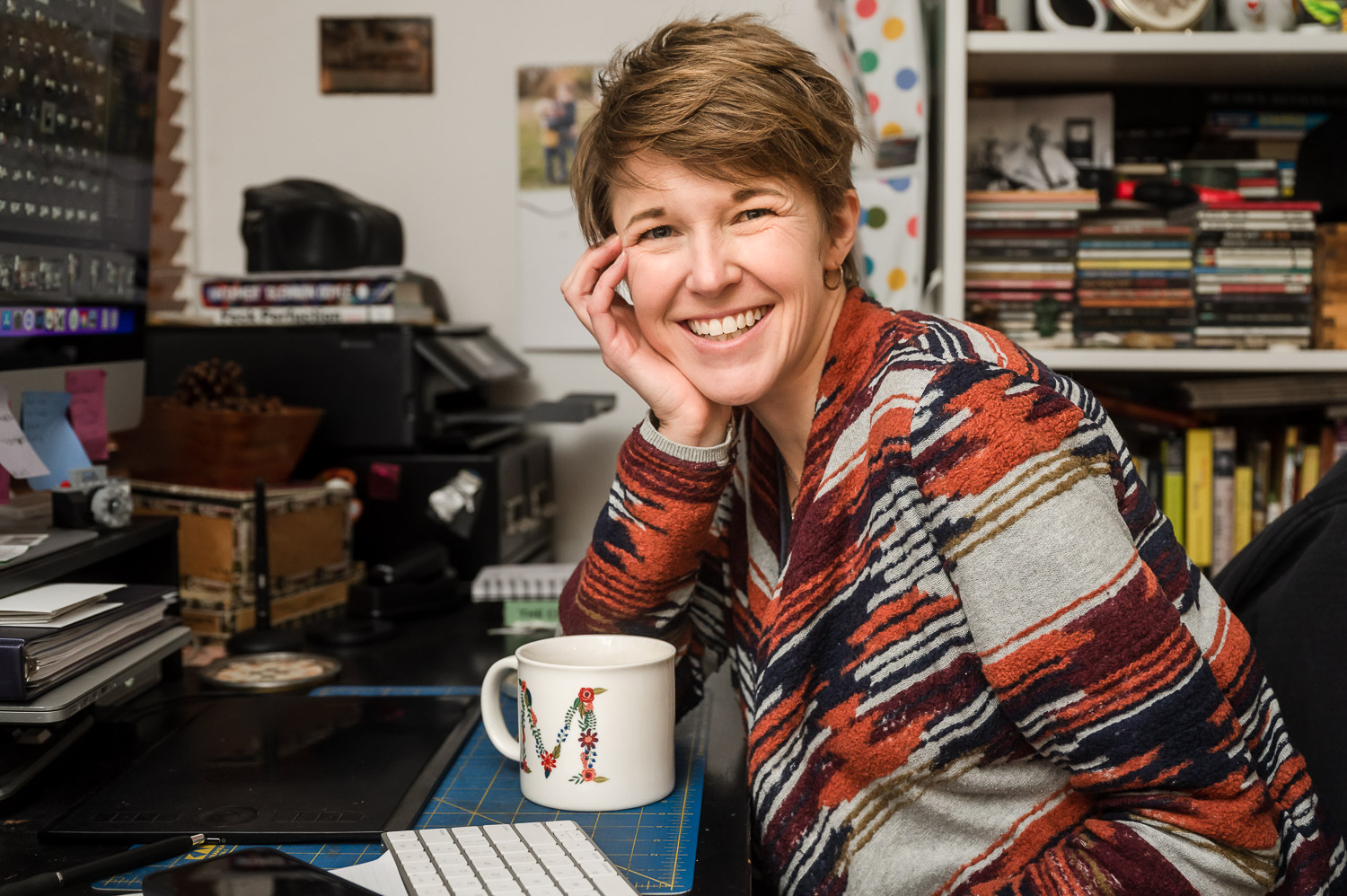 Maija Martin leaning on her desk in her messy office.