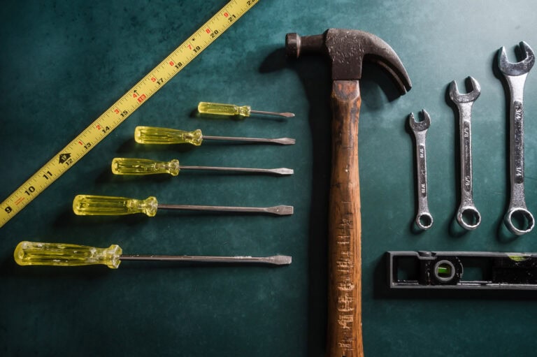 A variety of vintage tools laid out on dark forest green background.