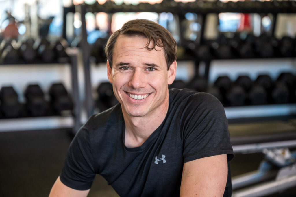 David Burnett of Finding Fitness - Headshot of man smiling in front of weight rack