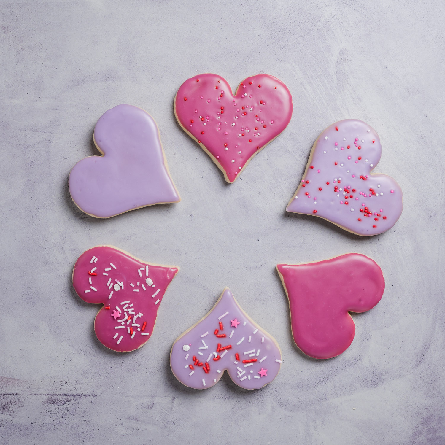 Six heart shaped sugar cookies arranged in a circle