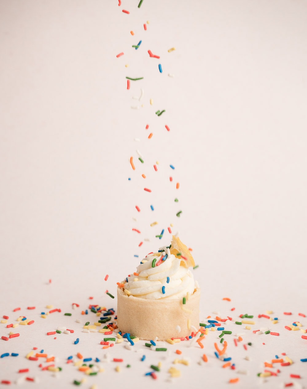 rainbow sprinkles falling onto a lemon custard tart made by the Whole Foods bakery