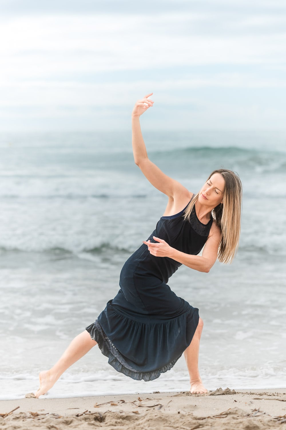 woman does yoga in a black dress on the beach at Lake Michigan