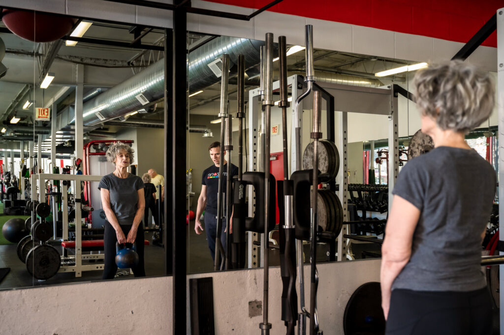 Reflection of David Burnett and client working out in gym in Chicago