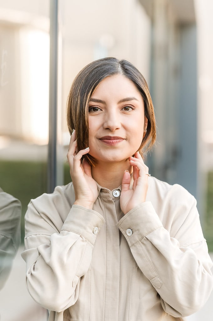 woman looks thoughtful as her hands frame her face while looking directly into the camera