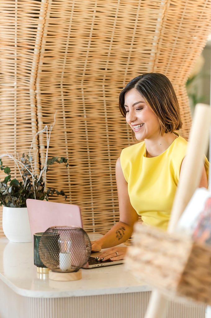 woman in yellow dress works with her clients at the computer