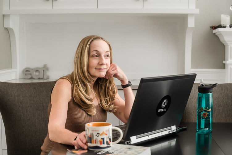 Woman on zoom call while drinking her morning coffee with her teal water bottle on the side