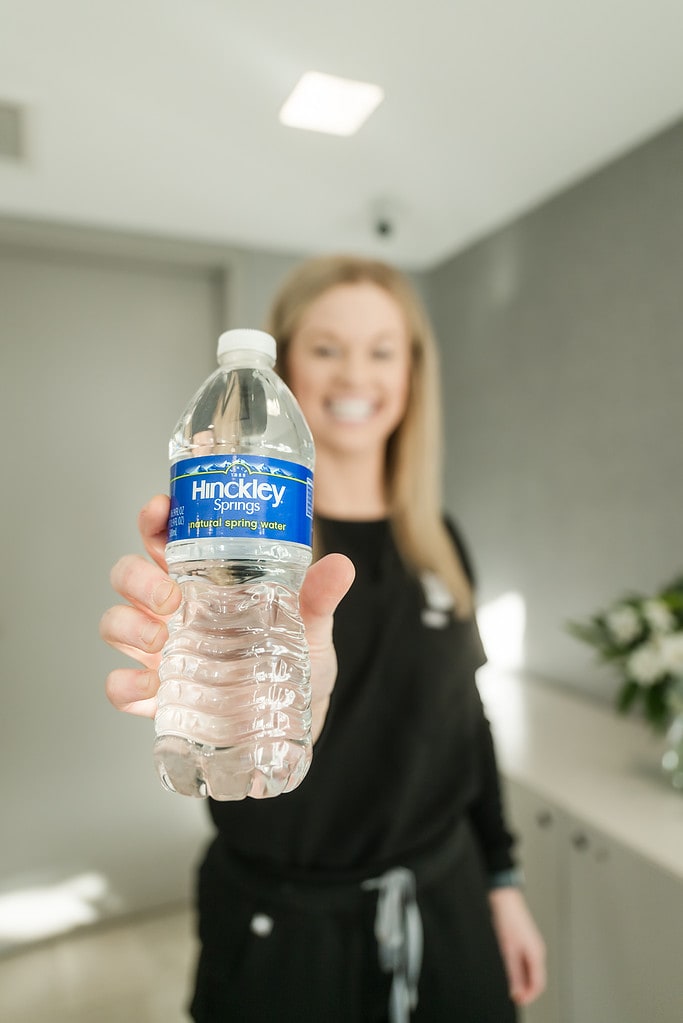 Receptionist hands client a bottle of Hinckley Springs water