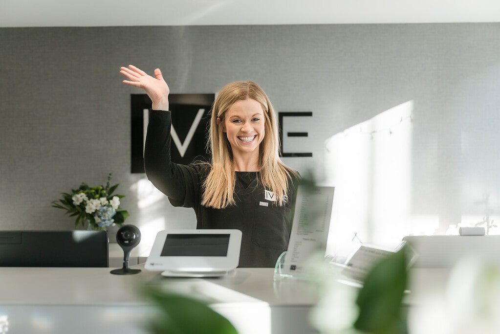 Receptionist at IVME Wellness + Aesthetics greets clients as they enter