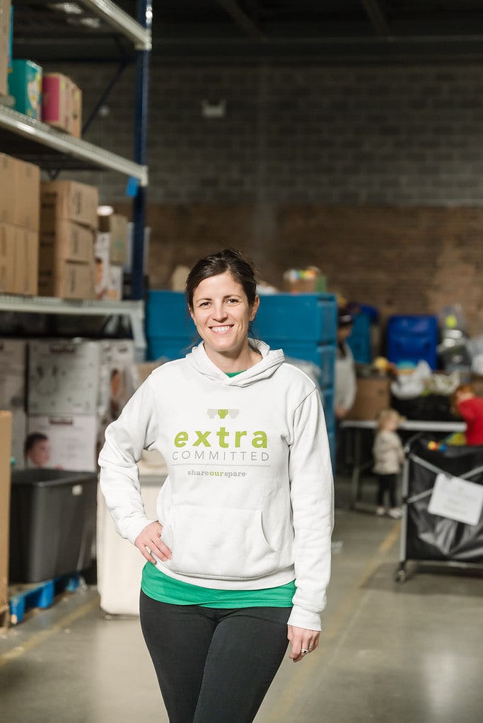 Alex Goodfellow stands in front of warehouse sorting event for volunteers at Share Our Spare