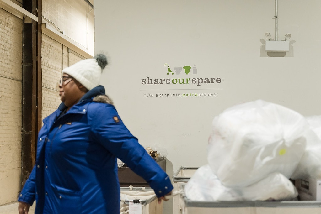 Woman rolls cart filled with diapers at a diaper distribution event for Share Our Spare