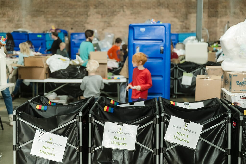 Volunteers sort clothing donations behind bins of clothing ready to be packed for families in need in Chicago