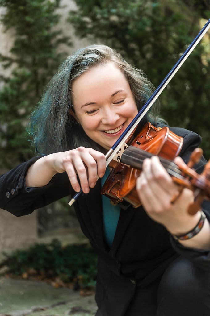 Woman with teal hair plays violin during a personal branding photography session