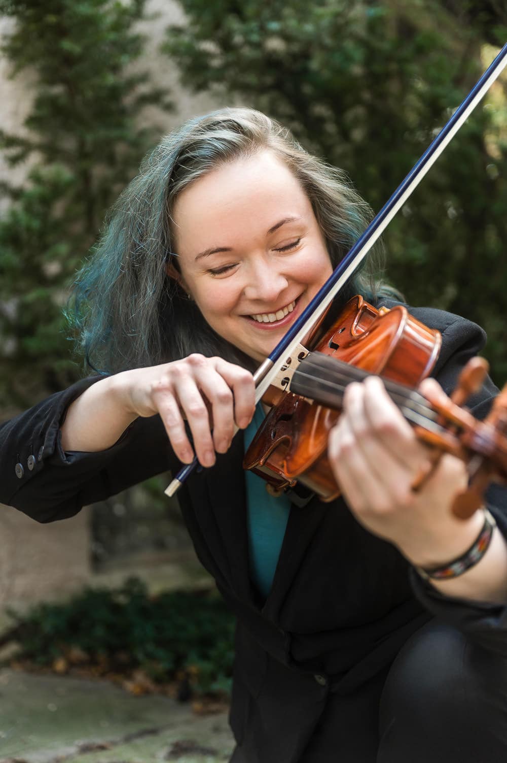 Woman with teal hair plays violin during a personal branding photography session