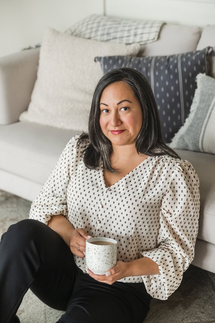 Woman leans against couch with cup of coffee