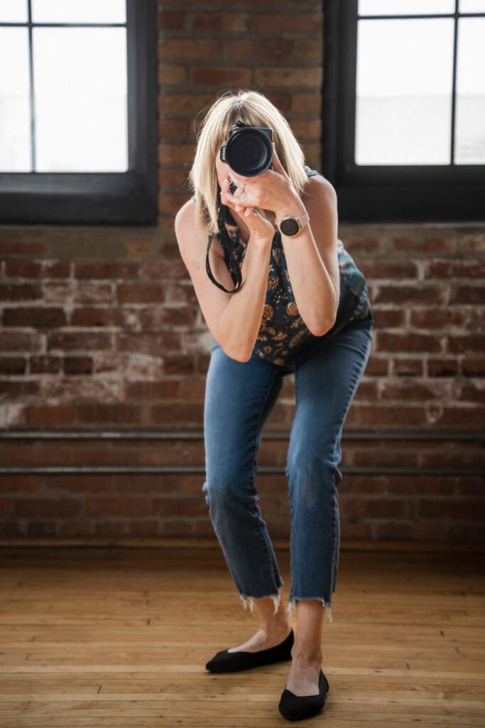 Maija Martin in teal top takes a photo of the viewer with her nikon mirrorless camera