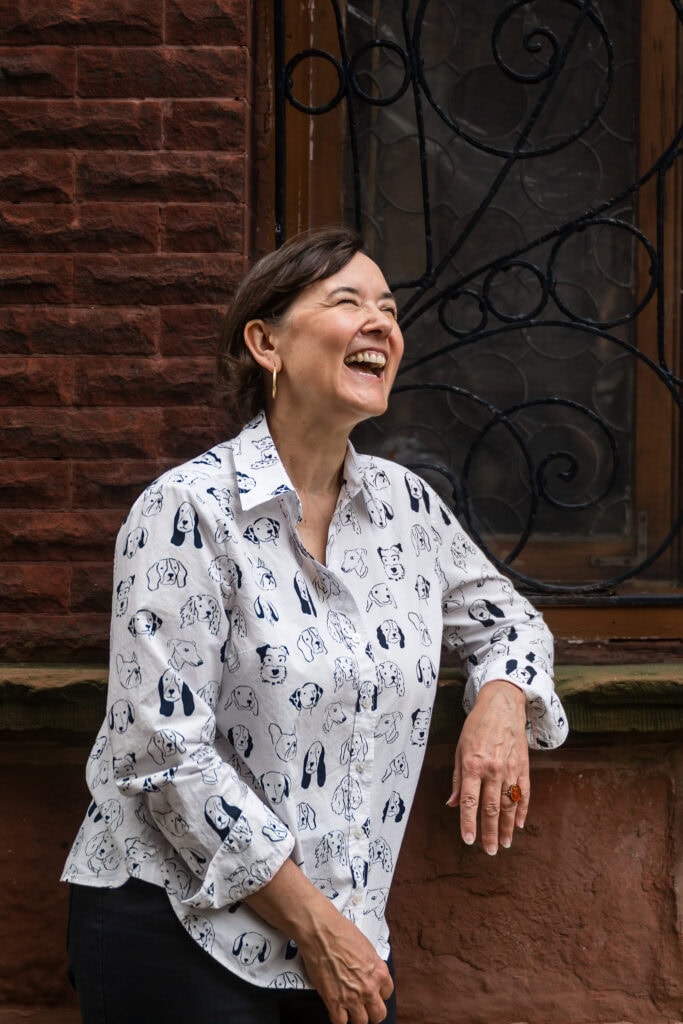 Vertical crop of woman stands in alley by a dark window textured background and laughs