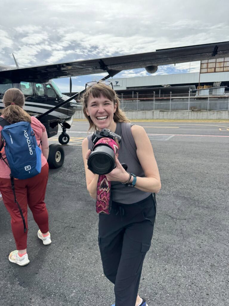Photo of Maija Martin of Chicago holding her camera in a behind-the-scenes moment on a recent brand photography trip to Costa Rica just as everyone was getting ready to board a small connector plane.